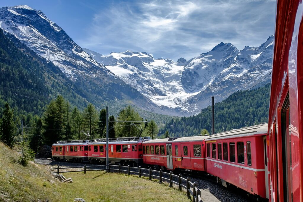 A train passing through the European countryside, seen from a quiet rural station.